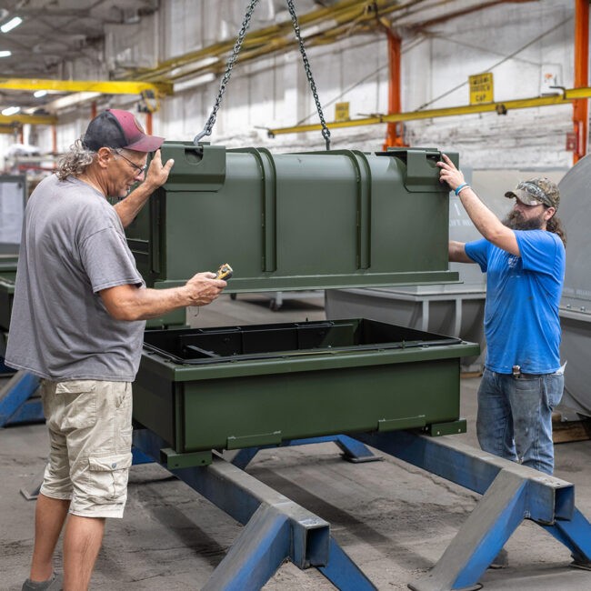 Workers putting together and inspecting a green container